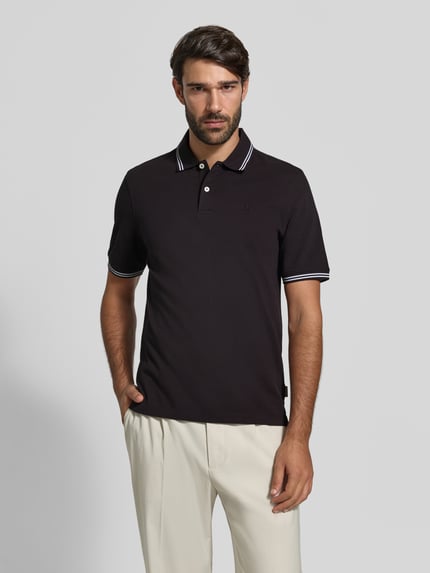 Männermodel trägt Slim Fit Poloshirt mit Label-Stitching von bugatti in Schwarz mit Polokragen, Knopfleiste, reine Baumwolle, Ganzkörperansicht von vorne.