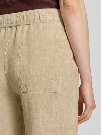 Frauenmodel trägt Leinenhose mit Bindegürtel Modell 'Chiara Belt' von MAC, beige Farbe, Struktur Leinen, Nahaufnahme Rückansicht. Damen Leinen, Wide Leg, Bundweite 39 cm, Innenbeinlänge 80 cm, Größe 36/32