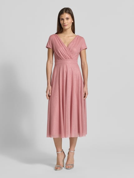 Vrouwenmodel draagt schimmerndes Cocktailkleid met V-hals van Vera Mont, tule, a-lijn, midi-jurk, glanzend, borstwijdte 42 cm, ruglengte 100 cm, maat 36, geheel vooraanzicht