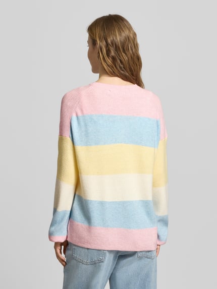 Frauenmodel trägt Regular Fit Strickpullover aus Viskose-Mix Modell 'ATIA' von Only mit mehrfarbigen Streifen, Stricktextur, Rundhalsausschnitt, langarm, Label Stitching, Ganzkörperansicht Rückansicht.