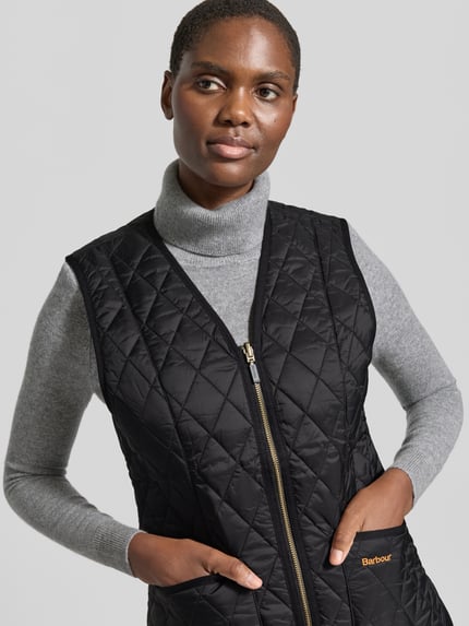 Frauenmodel trägt Regular Fit Weste mit V-Ausschnitt Modell 'BETTY' von Barbour, gesteppte schwarze Textur, Nahaufnahme Oberkörper, Damen Weste von Barbour