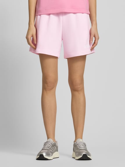 Frauenmodel trägt Shorts mit elastischem Bund und Tunnelzug von adidas Sportswear in Rosa, Logo, Baumwoll-Mix, Ganzkörperansicht von vorne.