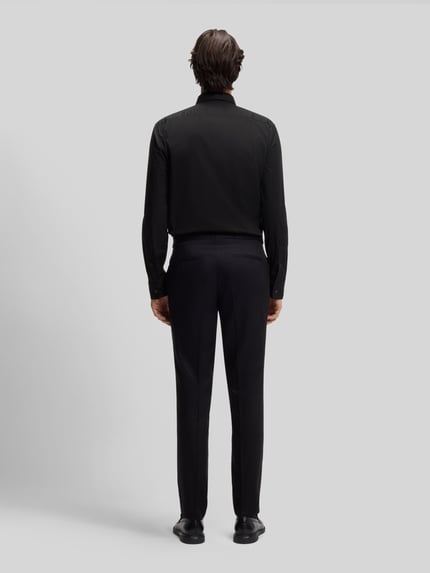 Męski model nosi Slim Fit Freizeithemd aus Baumwoll-Mix Modell 'ERMO' od HUGO, czarny, jednolity, długi rękaw, widok całej sylwetki z tyłu.