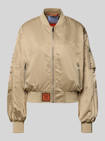 Produktfoto, Bomberjacke mit Reißverschlusstasche am Ärmel von Original Bombers in Beige mit Stehkragen, Logo-Stitching, Lockerer-Schnitt, glänzende Textur, Reißverschluss, Reißverschlusstasche, seitliche Eingrifftaschen mit Druckknopfverschluss, Label-Patch, elastische Abschlüsse, Rückenlänge 49 cm, Schulterbreite 50 cm, Brustweite 58 cm, Ärmellänge 61 cm.