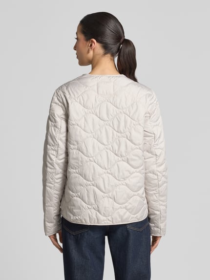 Männermodel trägt Steppjacke mit Rundhalsausschnitt von camel active w kolorze jasnobeżowym, z pikowaniem, prosty krój, listwa z zatrzaskami, długość tyłu w rozmiarze 36: 60 cm, szerokość ramion w rozmiarze 36: 43 cm, szerokość klatki piersiowej w rozmiarze 36: 53 cm, długość rękawów w rozmiarze 36: 64 cm, widok całej sylwetki z tyłu