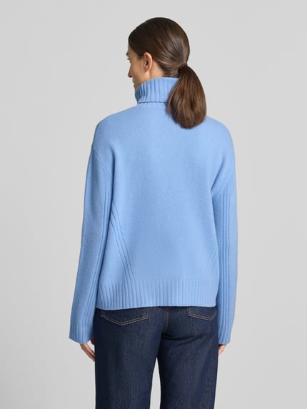 Frauenmodel trägt Relaxed Fit Rollkragenpullover aus reiner Wolle von Liu Jo White in Hellblau, gerippte Abschlüsse, Rückansicht, Ganzkörperansicht.