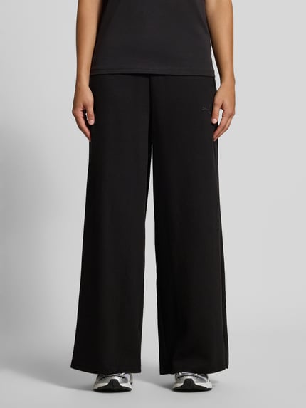 Frauenmodel trägt Relaxed Fit Sweathose aus reiner Baumwolle von PUMA, schwarz, weite Beinform, glatte Textur, Nahaufnahme Unterkörper, Damen Sweathose von PUMA.