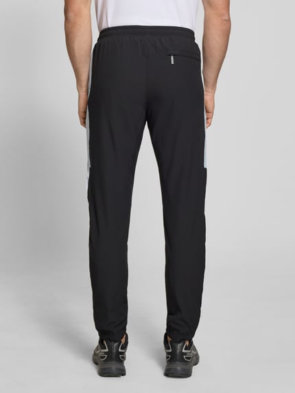Männermodel trägt Sweatpants mit Logo-Stitching Modell 'CASPIO' von SERGIO TACCHINI in Schwarz, Material-Mix mit Stretch-Anteil, Eingrifftaschen, körpernaher Schnitt, elastischer Bund mit Kordelzug, elastische Abschlüsse, Ganzkörperansicht Rückansicht.