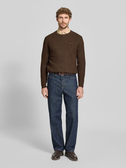 Männermodel trägt Regular Fit Pullover aus Baumwoll-Woll-Mix von GANT in Braun, kombiniert mit blauer Jeans, Ganzkörperansicht von vorne.