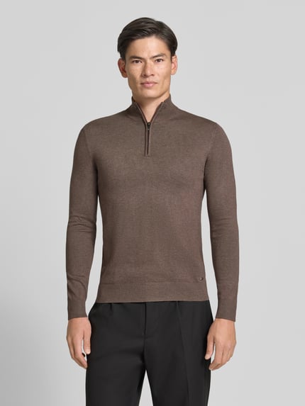 Männermodel trägt braunen Troyer mit Label-Applikation von MARKUP, Viskose-Mix, gerader Schnitt, gerippte Abschlüsse, Ganzkörperansicht von vorne.