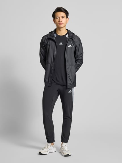 Męski model nosi T-Shirt z label-print od adidas Training, regular fit, okrągły ściągacz, czarny kolor, widok całej sylwetki z przodu.