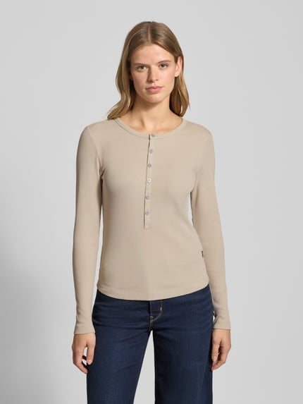 Frauenmodel trägt Slim Fit Longsleeve mit Rundhalsausschnitt und Knopfleiste von G-Star Raw in Beige, aus Baumwoll-Elasthan-Mix, Ganzkörperansicht von vorne.