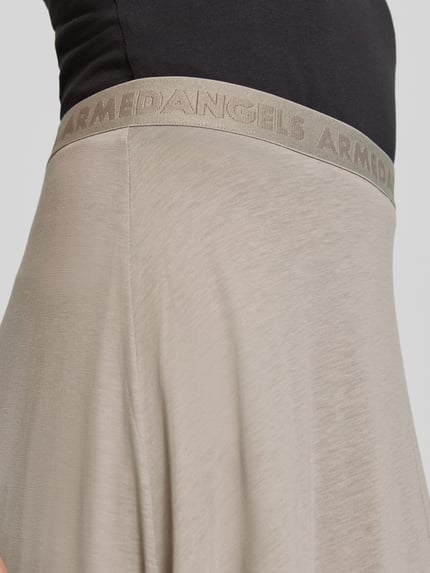 Frauenmodel trägt Loose Fit Midi-Rock aus Lyocell-Baumwoll-Mix Modell 'ILENIAA LARAA' von Armedangels in Beige mit feiner, glatter Textur, Damen Midi-Rock von Armedangels, Nahaufnahme Oberkörper.