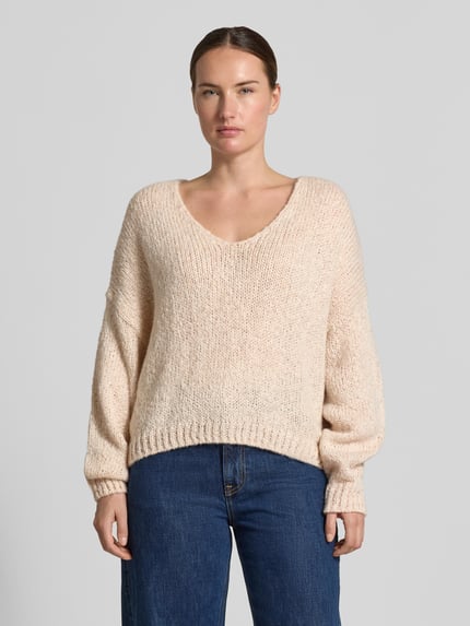 Frauenmodel trägt Oversized Strickpullover mit Mohair-Anteil von Oui in Beige, grobstrick mit V-Ausschnitt, Jeans, Nahaufnahme Oberkörper.
