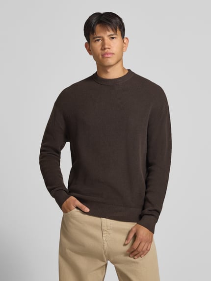 Männermodel trägt Regular Fit Strickpullover aus reiner Baumwolle von REVIEW, braun, strukturierte Oberfläche, Rundhalsausschnitt, Ganzkörperansicht von vorne.