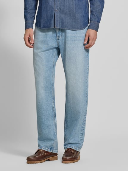 Männermodel trägt Baggy Fit Jeans mit Knopfverschluss von REVIEW aus reiner Baumwolle, 5-Pocket-Design, hellblaue Farbe, Ganzkörperansicht von vorne.