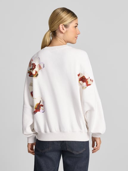 Vrouwenmodel draagt wit oversized sweatshirt uit puur katoen Model 'ASTERA' van DRYKORN met ribboorden en schoudernaden, volledige rugaanzicht.