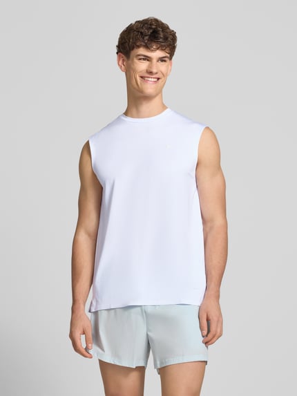 Männermodel trägt Relaxed Fit Top mit Logo-Print Modell 'OLIOS' von Ellesse, elastischer Material-Mix, helles Weiß, Rundhalsausschnitt, Ganzkörperansicht von vorne.