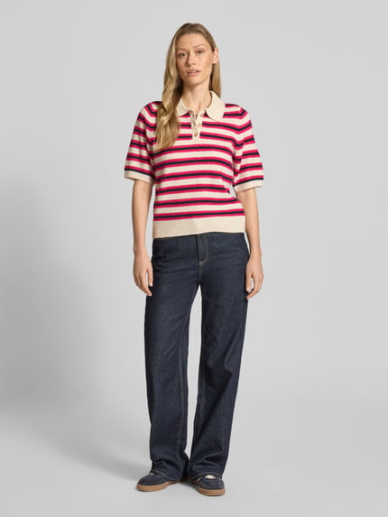 Frauenmodel trägt Regular Fit Strickpullover mit Woll-Anteil Modell 'CANNA' von Vero Moda, mehrfarbig gestreift, Polokragen, V-Ausschnitt, gerippte Abschlüsse, Stricktextur, Ganzkörperansicht von vorne.