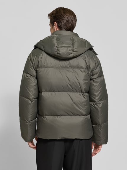 Männermodel trägt Regular Fit Daunenjacke mit abnehmbarer Kapuze von CK Calvin Klein, unifarben, wasserabweisend, Ganzkörperansicht Rückansicht.