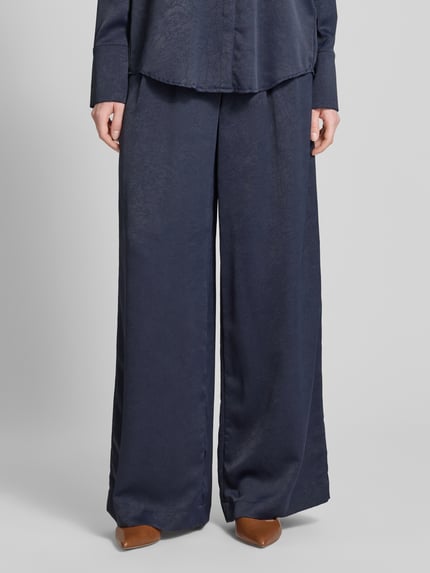 Vrouwenmodel draagt Wide Fit stoffen broek met structuurpatroon van Christian Berg Cocktail in donkerblauw met bandplooien, bloemenmotief, haakjes- en ritssluiting, bandwijdte maat 36: 40 cm, binnenbeenlengte maat 36: 80 cm, detailopname onderlichaam.