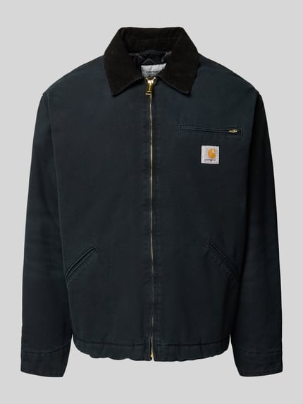 Produktfoto, schwarze Jacke mit Cord-Kentkragen, goldfarbenem Reißverschluss und Brusttasche, Jacke mit Brusttasche Modell 'DETROIT' von Carhartt Work In Progress, Regular Fit, sichtbarer Label-Patch, glatte Textur, klar strukturierte Formen, Vorderansicht.
