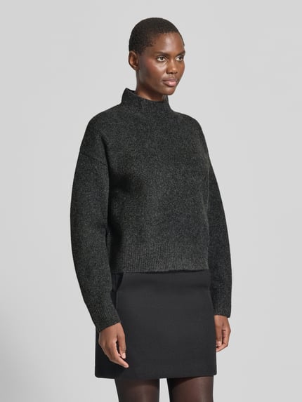 Frauenmodel trägt Turtleneck-Pullover mit Woll-Anteil und Rundhalsausschnitt von Neo Noir, dunkles Grau, gerader Schnitt, Nahaufnahme Oberkörper.