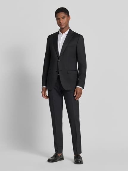 Männermodel trägt Anzughose mit Bügelfalten Modell 'Apollo' von DIGEL, schwarz, Material-Mix mit Schurwoll-Anteil, Slim-Fit, Ganzkörperansicht von vorne.