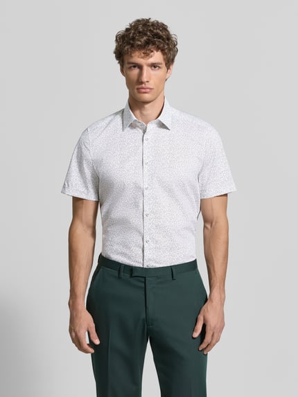 Männermodel trägt Slim Fit Business-Hemd mit Kentkragen von OLYMP Level Five, weiß mit Muster, Knopfleiste, Baumwoll-Mix mit Stretch-Anteil, Ganzkörperansicht von vorne.