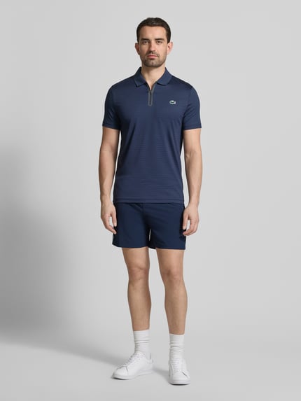 Männermodel trägt Loose Fit Sport-Shorts mit Mesh-Bund von Lacoste Sport, unifarben, Logo-Stitching, Ganzkörperansicht von vorne.