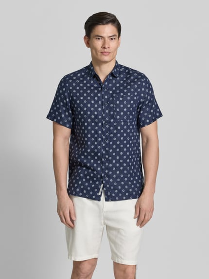 Männermodel trägt Regular Fit Leinenhemd mit Brusttasche von Scotch & Soda, dunkelblau mit Allover-Motiv-Print, Ganzkörperansicht von vorne. Reine Leinen, Regular-Fit, Brusttasche, Kentkragen, Kurzärmelig, durchgehende Knopfleiste, Logo-Patch, Rückenlänge bei Größe M: 75 cm, Schulterbreite bei Größe M: 42 cm, Ärmellänge bei Größe M: 24 cm.