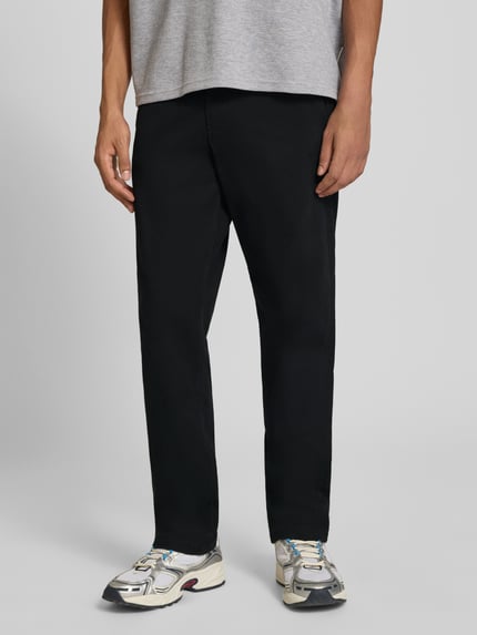 Mannenmodel draagt zwarte straight fit broek van katoenmix Model 'Kane' van JACK & JONES met gulp- en achterzak, voorkant halve lichaamsopname. Context: Heren broek van JACK & JONES, elastische katoenmix, straight fit, Model 'Kane', gulp- en achterzak, knoop- en ritssluiting, bandwijdte bij maat 32/32: 41 cm, binnenbeenlengte bij maat 32/32: 77 cm.