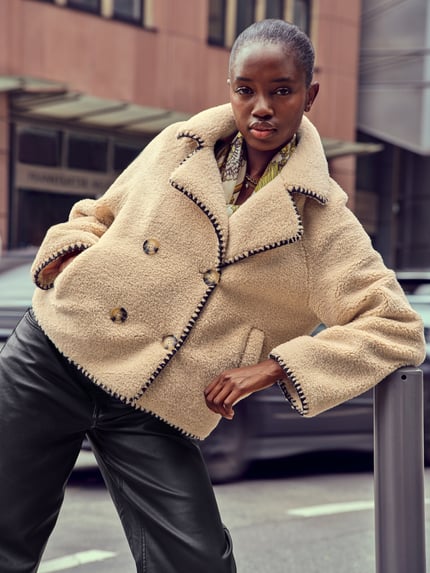 Frauenmodel trägt Jacke aus Teddyfell mit Eingrifftaschen von Apricot in Beige, Zweireiher, Relaxed-Fit, Reverskragen, Nahaufnahme Oberkörper. Rückenlänge bei Größe S: 64 cm, Schulterbreite: 47 cm, Brustweite: 60 cm, Ärmellänge: 64 cm.