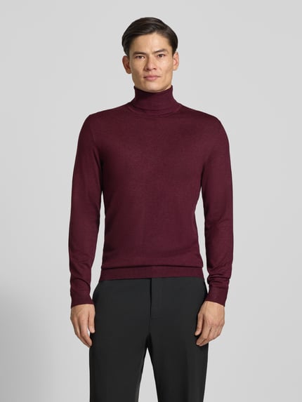 Männermodel trägt Slim Fit Rollkragenpullover aus Viskose-Mix mit Rippbündchen von MCNEAL in Dunkelrot, Ganzkörperansicht von vorne.