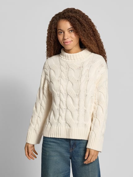 Frauenmodel trägt Regular Fit Strickpullover aus Baumwoll-Mix von Gina Tricot in Creme mit Zopfmuster und Stehkragen, Ganzkörperansicht von vorne. Rückenlänge 62 cm, Ärmellänge 53 cm.