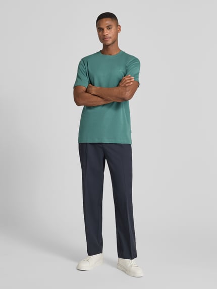 Männermodel trägt T-Shirt mit Label-Stitching Modell 'Priamo' von JOOP! Collection in Grün, reine Baumwolle, Regular Fit, Ganzkörperansicht von vorne.