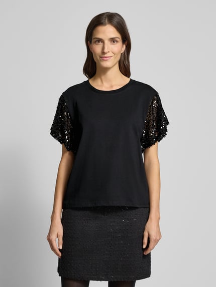 Frauenmodel trägt T-Shirt mit geripptem Rundhalsausschnitt Modell 'WINGS' von FREE/QUENT aus schwarzer Baumwolle mit Pailletten, Ganzkörperansicht von vorne.