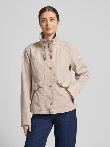 Modelka kobieca ma na sobie Regular Fit Jacke mit Logo-Patch od Gil Bret, jasnobeżowy kolor, stehkraag z tunelem, kieszenie na zamek, przód z zakładką, długość tyłu w rozmiarze 36: 64 cm, szerokość ramion w rozmiarze 36: 41 cm, szerokość w biuście w rozmiarze 36: 46 cm, długość rękawa w rozmiarze 36: 65 cm, przód w pełnym widoku.