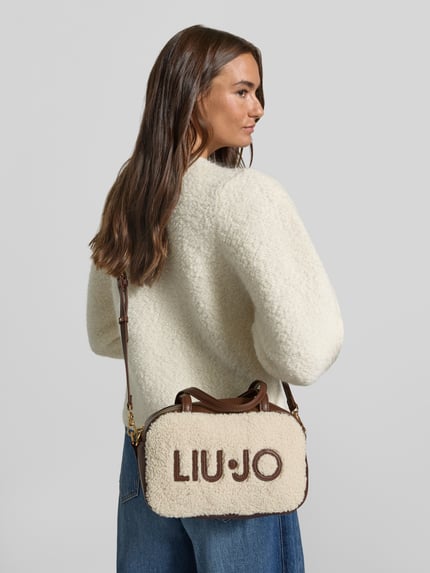 Frauenmodel trägt Handtasche aus Teddyfell Modell 'FERIELLE' von Liu Jo White, Logo, Schulterriemen, Naturtöne, Rückansicht