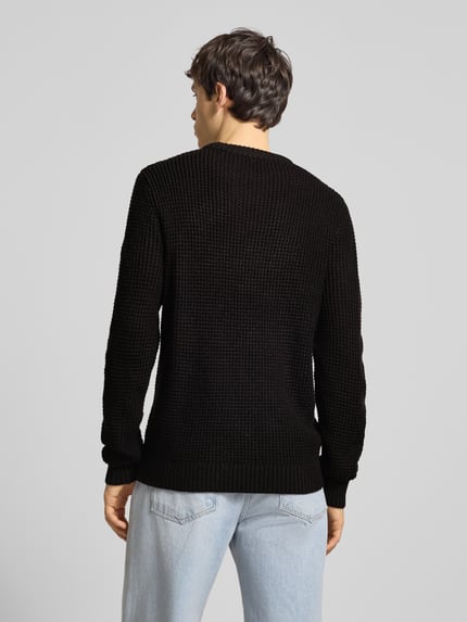 Männermodel trägt schwarzen Strickpullover mit gerippten Abschlüssen Modell 'LIAM' von Jack & Jones, lockerer Sitz, Rückansicht, Herrenmode.