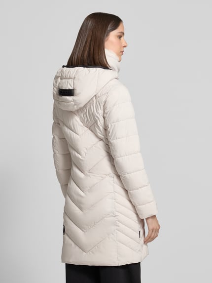 Frauenmodel trägt Steppjacke mit Zweiwege-Reißverschluss Modell 'COSETTE' von khujo in Creme, Kapuze und Stehkragen, Ganzkörperansicht Rückansicht. Slim Fit, Reißverschlusstaschen, sichtbare Steppnähte und glatte Textur. Rückenlänge 90 cm, Schulterbreite 35 cm, Brustweite 48 cm, Ärmellänge 62 cm.