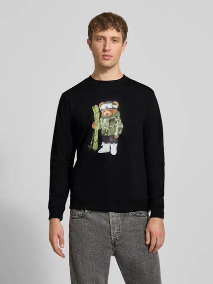Mężczyzna nosi Sweatshirt mit Motiv-Print od CHILL PILL, czarny kolor, mieszanka bawełny, krój regular fit, okrągły dekolt, długość tyłu w rozmiarze M 68 cm, długość rękawów 66 cm, Ganzkörperansicht von vorne.