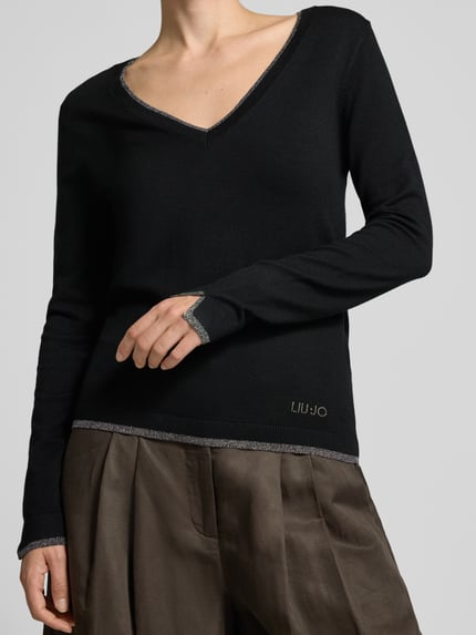 Frauenmodel trägt Slim Fit Longsleeve aus reine Viskose Modell 'Maglia Chiusa' von Liu Jo White in Schwarz mit V-Ausschnitt, Logo-Detail, Nahaufnahme Oberkörper.