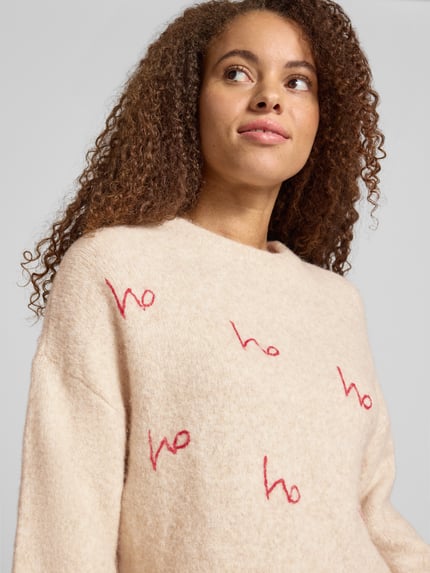 Frauenmodel trägt beige Relaxed Fit Strickpullover mit Rundhalsausschnitt Modell 'VIXEN' von NOISY MAY, Materialmix mit Woll-Anteil, Nahaufnahme Oberkörper.