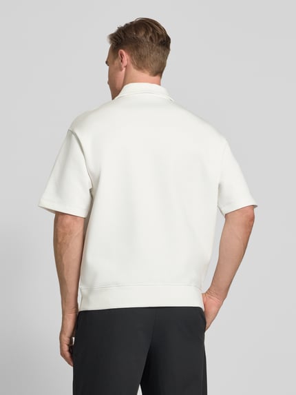 Männermodel trägt Loose Fit Poloshirt mit Label-Stitching von ARMANI EXCHANGE aus Baumwoll-Mix mit Stretch-Anteil, Ganzkörperansicht Rückansicht.