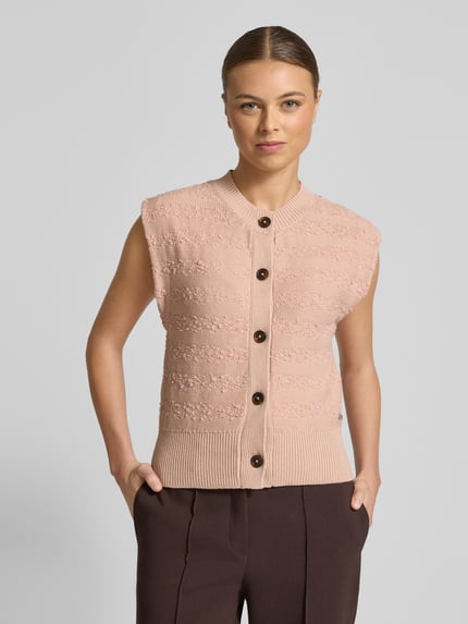 Frauenmodel trägt Strickweste mit Rundhalsausschnitt von Scotch & Soda aus Baumwoll-Mix, Slim-Fit, Knopfleiste, Ganzkörperansicht von vorne.