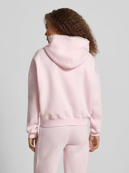 Frauenmodel trägt Hoodie mit Häkelspitzenbesatz von REVIEW in Rosa, lockere Passform, Baumwollmischung, Rückansicht, KI-modifiziertes Bild.
