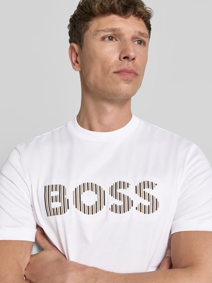 Mężczyzna nosi Regular Fit T-Shirt aus reiner Baumwolle Modell 'C-THOMPSON 41' von BOSS, biały, jednolity, krótki rękaw, okrągły dekolt, merceryzowana bawełna, aplikacja z logo na piersi, zbliżenie na górną część ciała