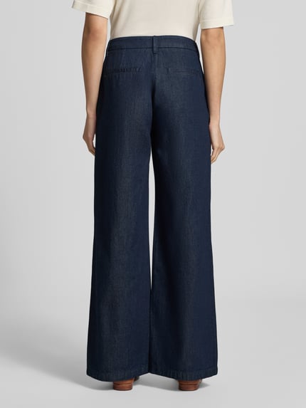 Frauenmodel trägt Wide Leg Jeans mit Lyocell-Anteil von COMMA, dunkelblauer Baumwoll-Lyocell-Mix, angedeutete Taschen, Ganzkörperansicht Rückansicht.
