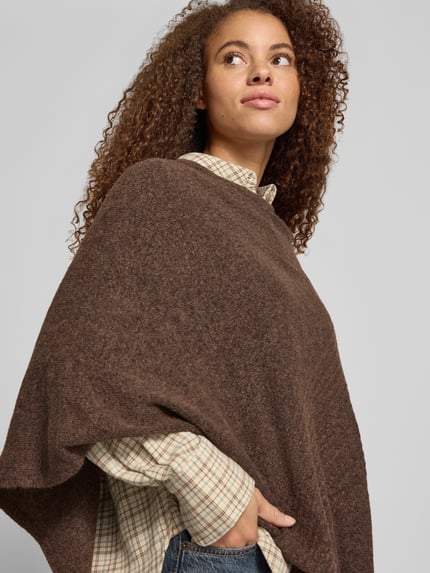 Frauenmodel trägt Poncho mit asymmetrischem Saum von PIECES, Melange-Optik, Strick, Rundhals, braune Töne, Nahaufnahme Oberkörper